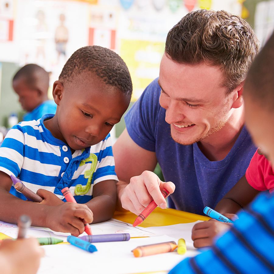 Man volunteering helping children learn